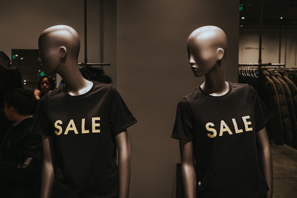 Two mannequins wearing 'SALE' shirts