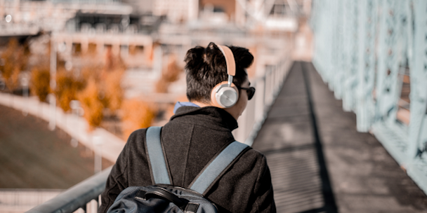 A man walks on a bridge with headphone on