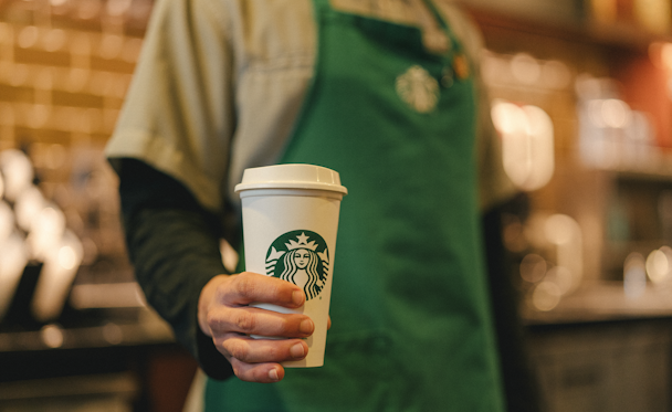Starbucks barista holding a takeaway coffee
