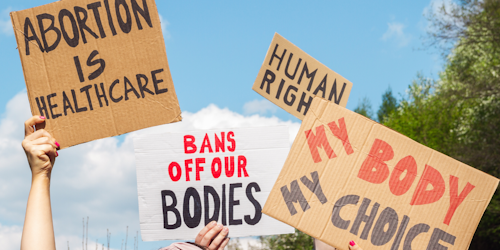 abortion backers hold up signs that read "my body my choice" and "bans off our bodies"