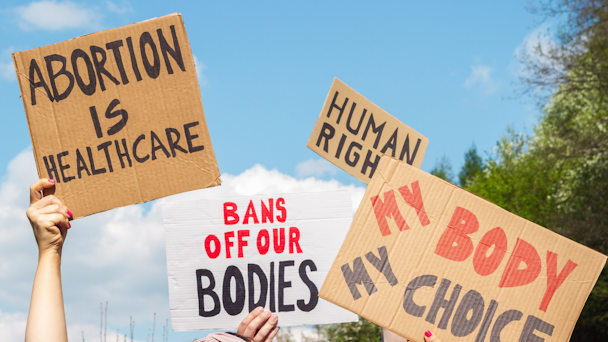 abortion backers hold up signs that read "my body my choice" and "bans off our bodies"