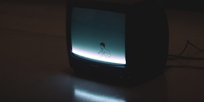 Old CRT TV in darkness showing cartoon boy on blue background