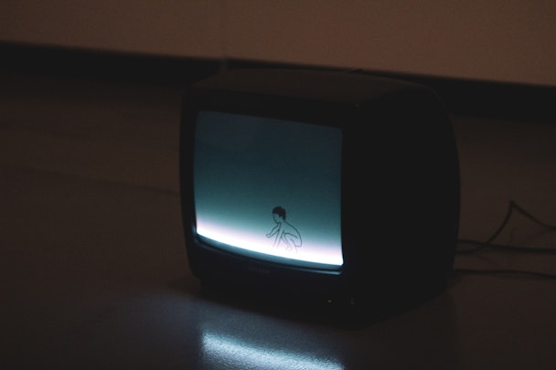 Old CRT TV in darkness showing cartoon boy on blue background