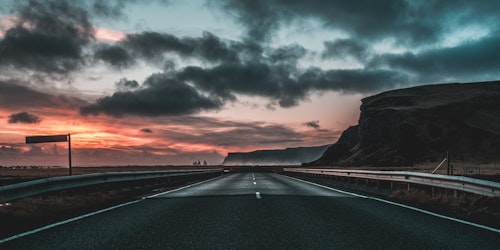 Long road underneath cloudy sky at sunset in Vik, Iceland