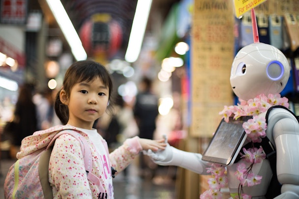 Little girl making friends with a robot