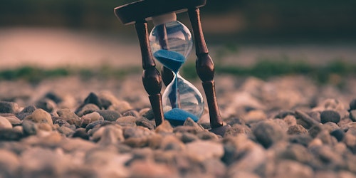 Hourglass containing blue sand on beach