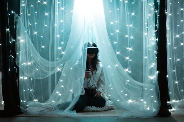 Woman using VR headset, surrounded by fairy lights