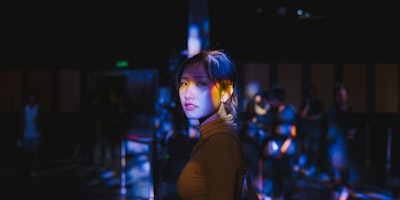 Asian woman in focus against dark background