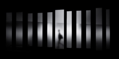 Blurred grayscale image of person running through panels