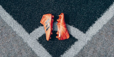 Orange football boots on gray astroturf