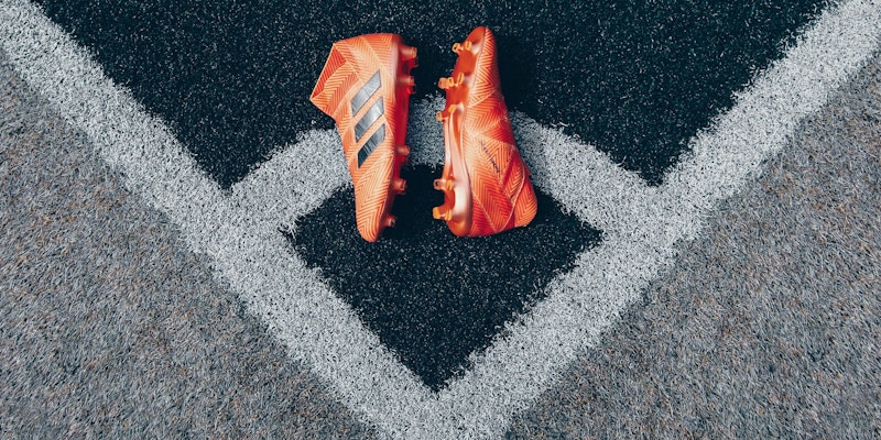 Orange football boots on gray astroturf