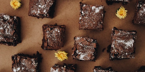 Brownies on parchment paper with scattered dandelions