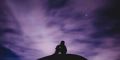 Man sat underneath starry night sky