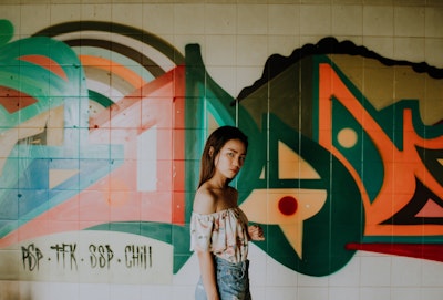Woman standing in front of graffiti'd tiles