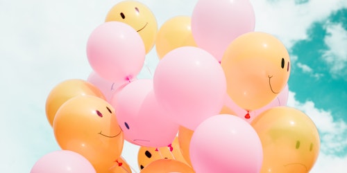 Pink and orange balloons with (mostly) smiley faces
