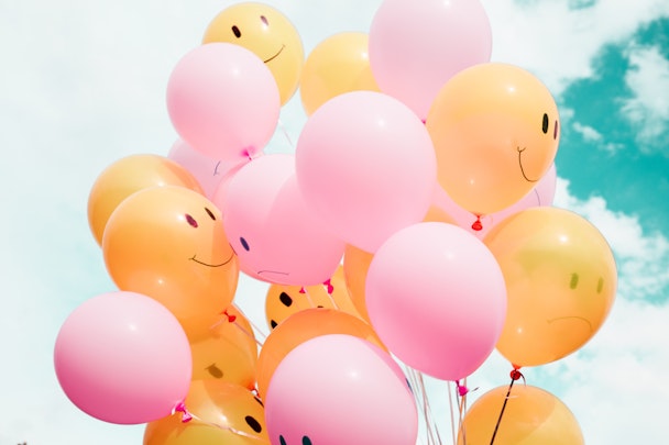 Pink and orange balloons with (mostly) smiley faces