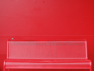 Empty red metal bench against red wall