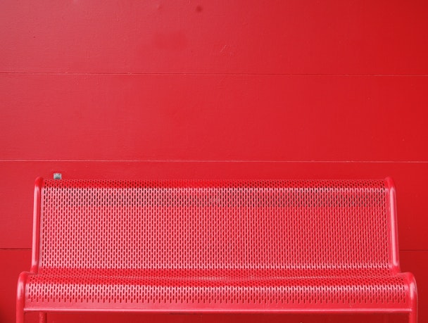 Empty red metal bench against red wall