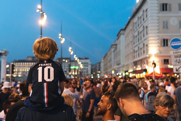 Boy on dad's shoulders wearing a France football shirt