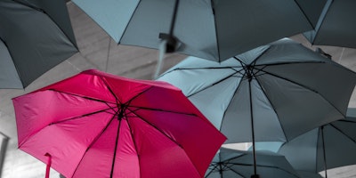 Red umbrella surrounded by grey umbrellas