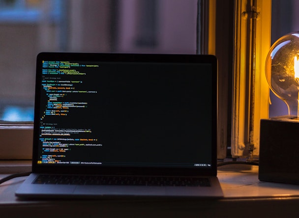 Code on laptop screen next to lamp