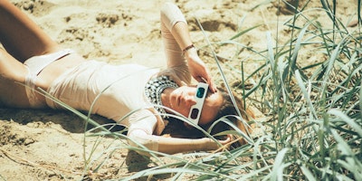 Woman lying in grass wearing 3D glasses