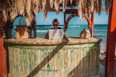Woman working on laptop at beach bar