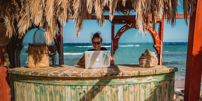 Woman working on laptop at beach bar