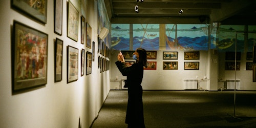 Woman wearing face mask taking a photo at an art exhibiton