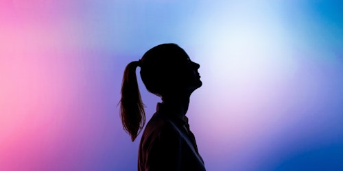 Black silhouette of a woman against pink and blue background