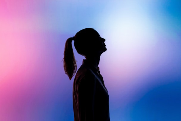 Black silhouette of a woman against pink and blue background