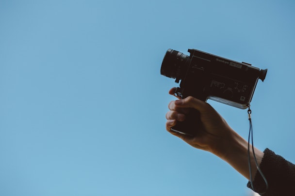 Person holding video camera against blue background