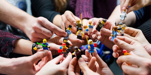 People stood in a circle holding lego people