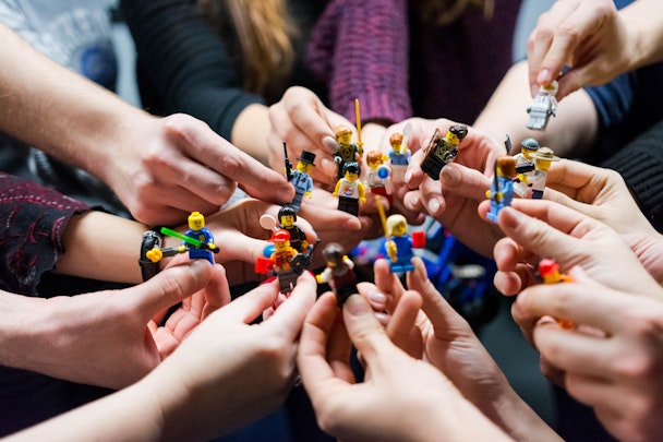People stood in a circle holding lego people