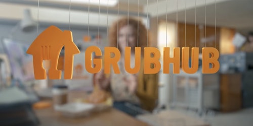Grubhub orange branding and logo with woman blurred in the background