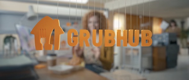 Grubhub orange branding and logo with woman blurred in the background