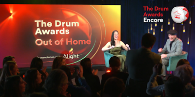 On stage at The Drum Awards for Out of Home, Rise New York & Partners is awarded. Cheering crowds are seen in the foreground as the winner is announced by excited hosts.