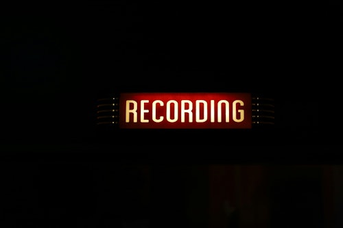 A red and white sign shows the word 'recording' against a black background