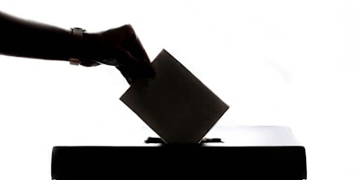 A hand places a voting paper into a ballot box