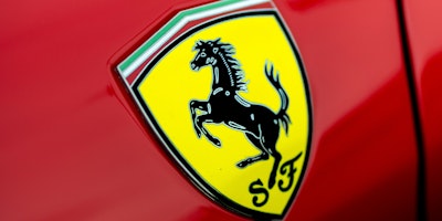 A close-up of a Ferrari badge against a Ferrari red background