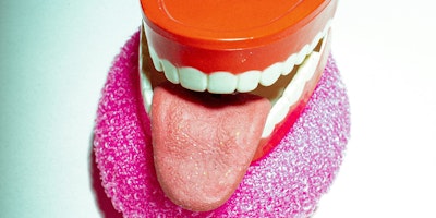 A model mouth and tongue with red gums against a white background