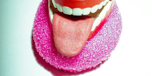 A model mouth and tongue with red gums against a white background