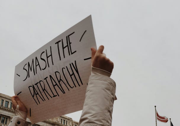 Two hands hold up a sign that reads 'smash the patriarchy' Two hands hold up a sign that reads 'smash the patriarchy'