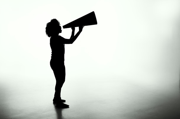 A silhouette of a young person holding a megaphone against a white background