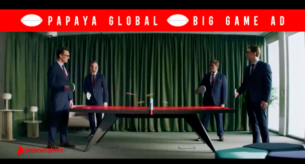 A still from Papaya Global's Super Bowl ad showing four men in business suits playing ping pong