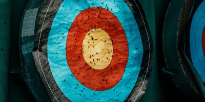 An archery target with arrow marks against a green background