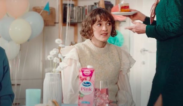 A woman sits at a table at a party with a carton of juice in front of her A woman sits at a table at a party with a carton of juice in front of her