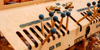 A series of levers with blue knobs on an old piece of machinery