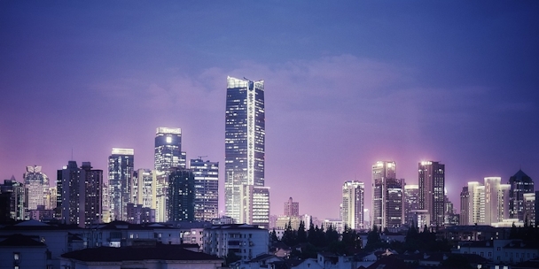 Photograph of Shanghai city at night with skyscrapers lit up against a purple-blue sky Photograph of Shanghai city at night with skyscrapers lit up against a purple-blue sky