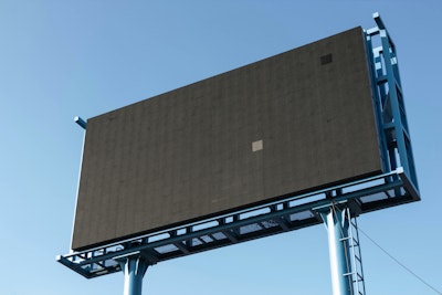A blank digital billboard in front of a blue sky